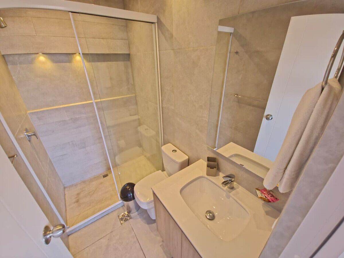 Une salle de bain moderne avec une douche à parois de verre, des toilettes, un lavabo et un miroir.