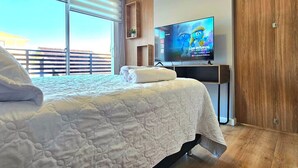 Une chambre à coucher avec un grand lit, un téléviseur posé sur un meuble et une armoire en bois.