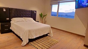 Une chambre à coucher avec un lit, une table de chevet, un téléviseur et une fenêtre donnant sur un beau paysage.