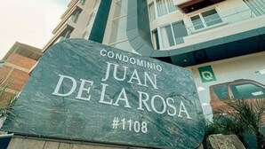 Une enseigne indiquant « Condominio Juan de la Rosa, no 1108 », avec un immeuble moderne en arrière-plan.