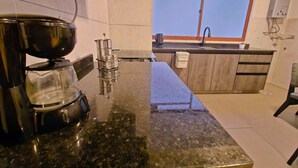 Eine Küche mit Granitarbeitsplatte, einer Kaffeemaschine, einem Fenster und einem Spülbecken.