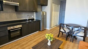 A modern kitchen with dark cabinets, stainless steel appliances, and a wooden dining table with chairs.