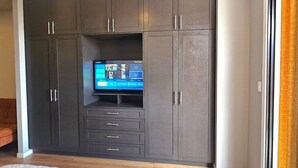 A dark-colored wardrobe with multiple compartments and a television screen displaying a game.