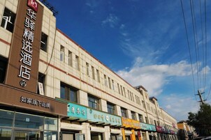 Fachada de hotel con varios comercios en la planta baja, con letreros en un idioma extranjero.