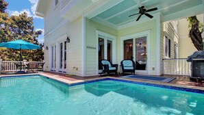 Une piscine avec deux chaises et un ventilateur de plafond, le tout situé sur une terrasse couverte.