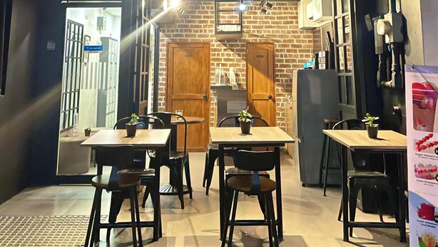 Un ristorante con pareti in mattoni e porte in legno, tavoli e sedie disposti per la ristorazione.