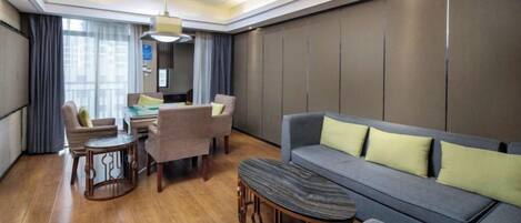 A modern hotel room with a sofa, a dining table, and a small coffee table.