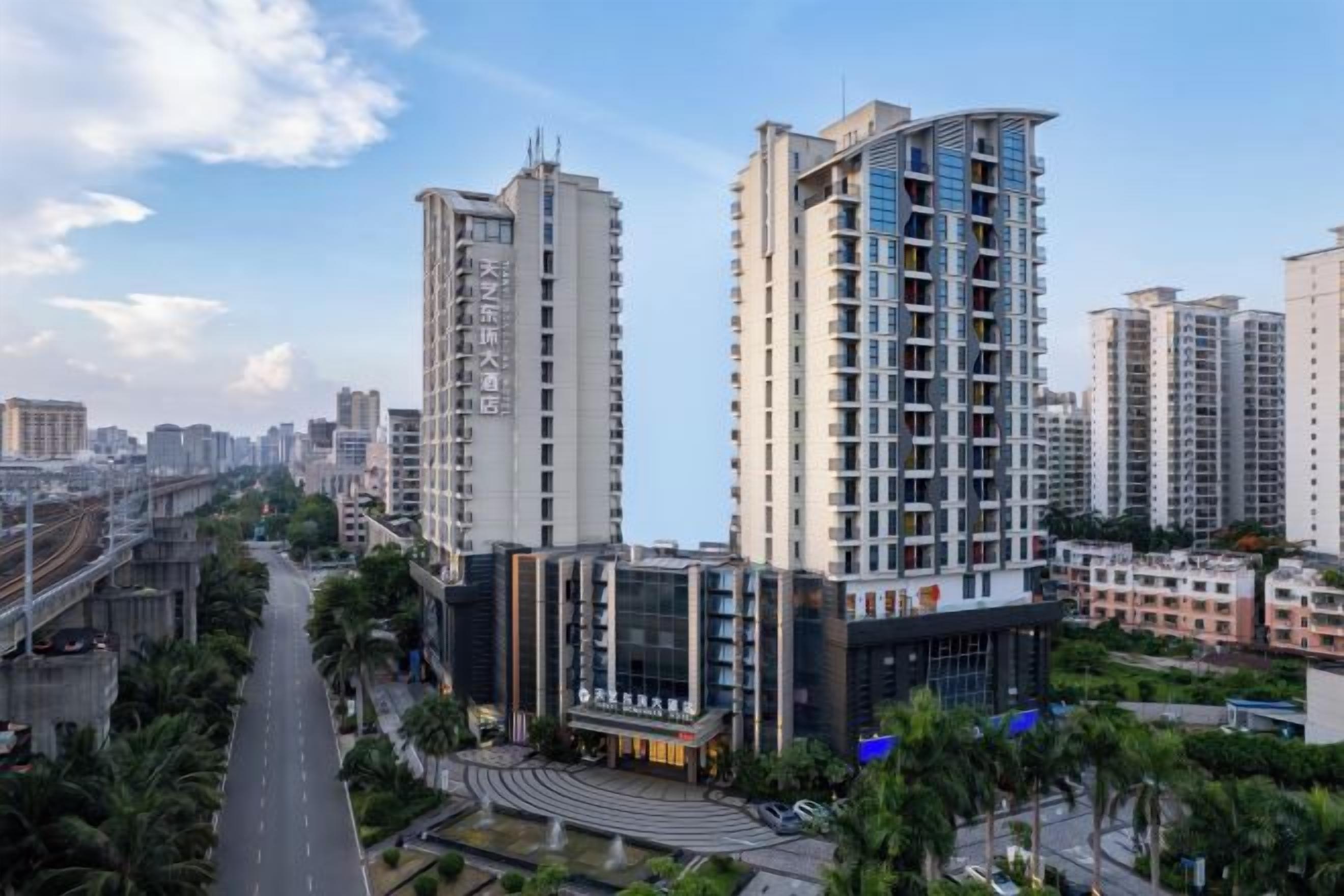 A high-rise building with multiple floors, surrounded by greenery and other buildings.