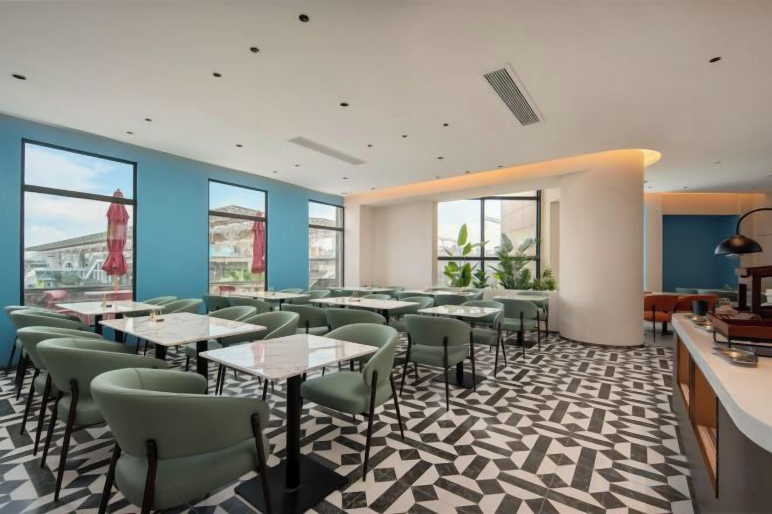 A modern dining area with tables and chairs, large windows, and a patterned floor.