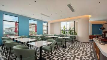 A modern dining area with tables and chairs, large windows, and a patterned floor.
