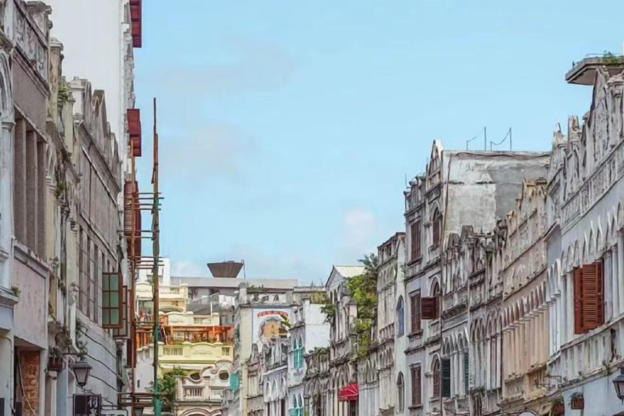 Une rue étroite bordée de bâtiments historiques, dont certains sont entourés d’échafaudages.