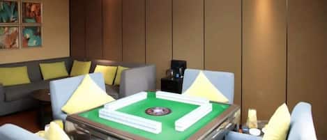 A room with a green pool table, sofas, and a coffee machine.