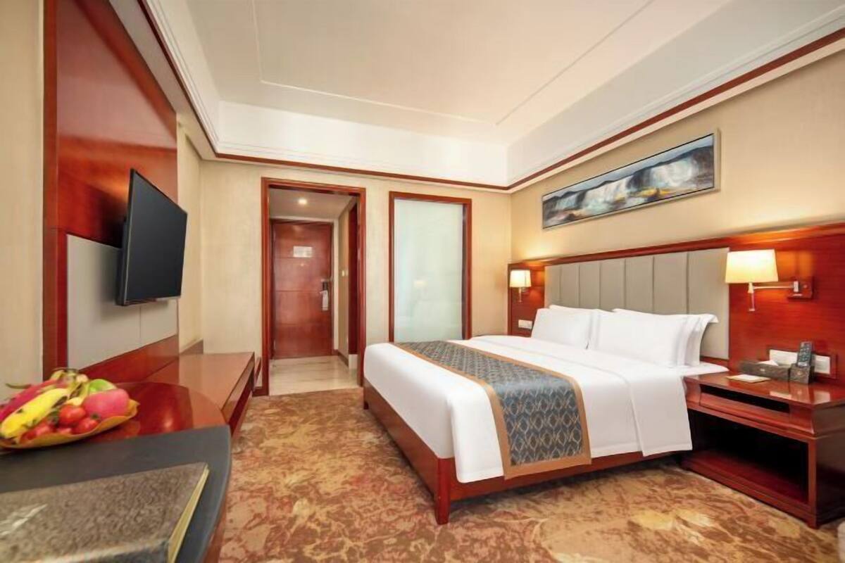 Ein Hotelzimmer mit Bett, Nachttisch, Fernseher und Obstschale.