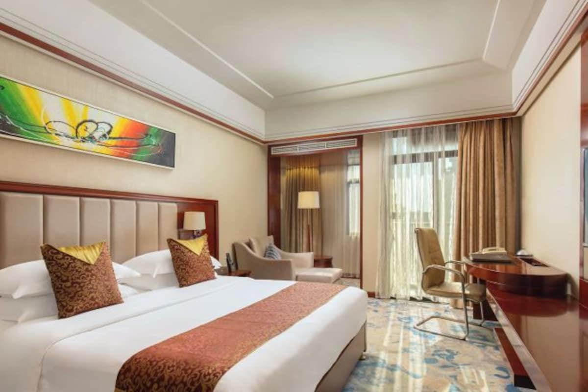 Habitación de hotel con una cama grande, un escritorio, una silla y un cuadro en la pared.