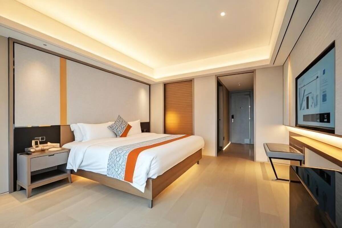 Ein modernes Hotelzimmer mit einem großen Bett, Nachttischen, einem Flachbildfernseher und Holzboden.