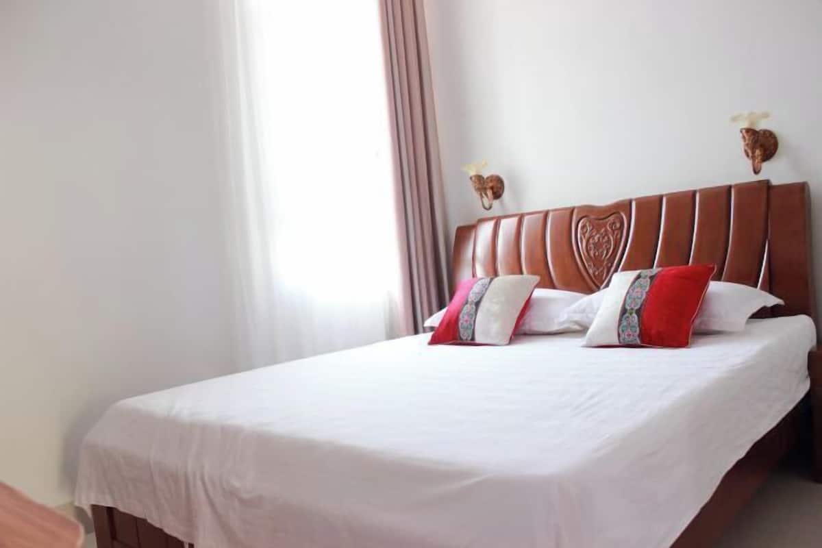 A neatly made bed with a wooden headboard, white bedding, and decorative pillows.