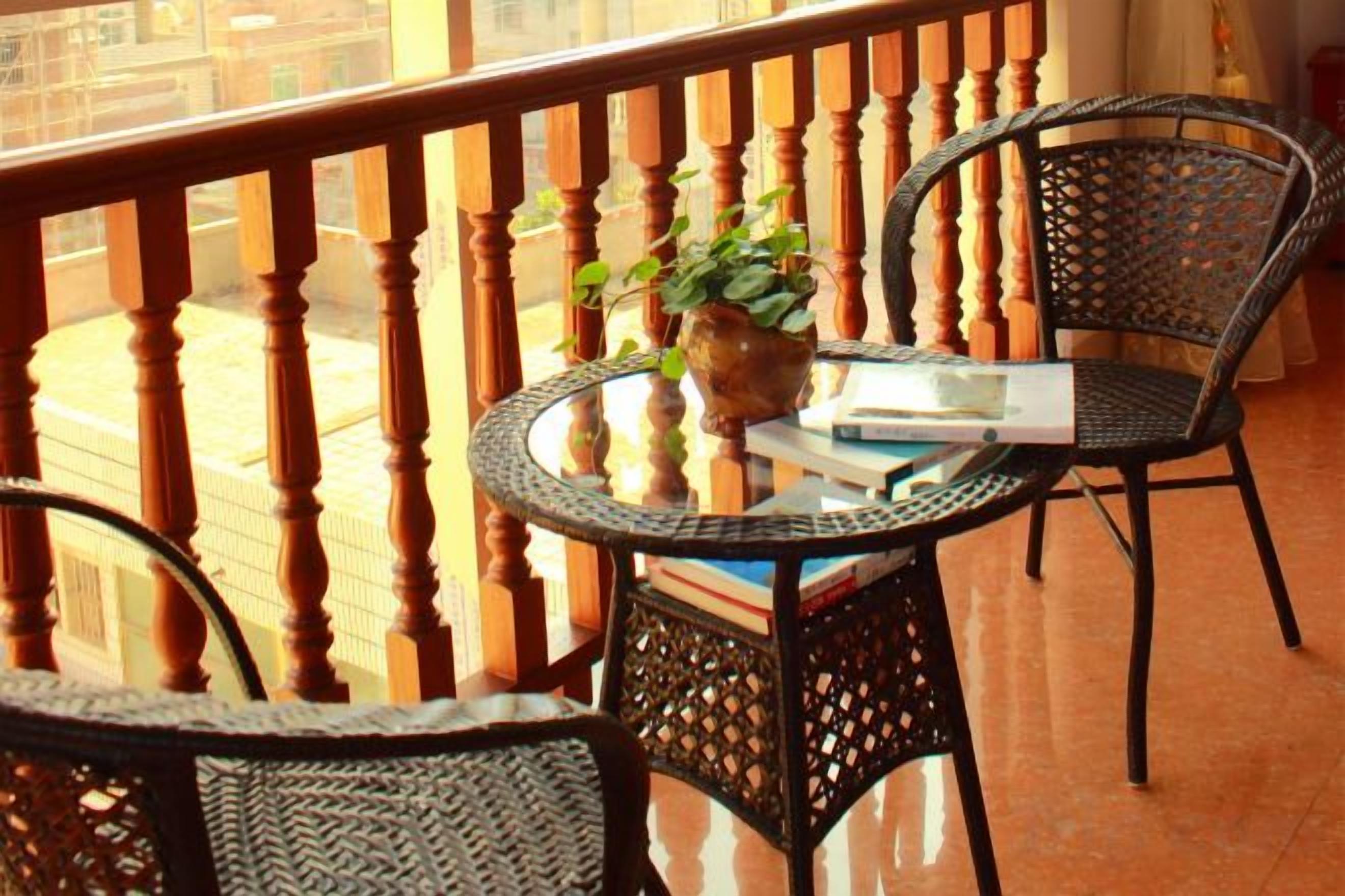 A balcony with a round table, two chairs, a potted plant, and a book.