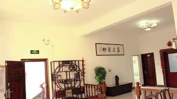 A hotel lobby with a staircase, a reception desk, and a wall-mounted sign.
