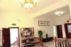 A hotel lobby with a staircase, a reception desk, and a wall-mounted sign. - Meizhoudao Qingtianjian Hostel (Putian)