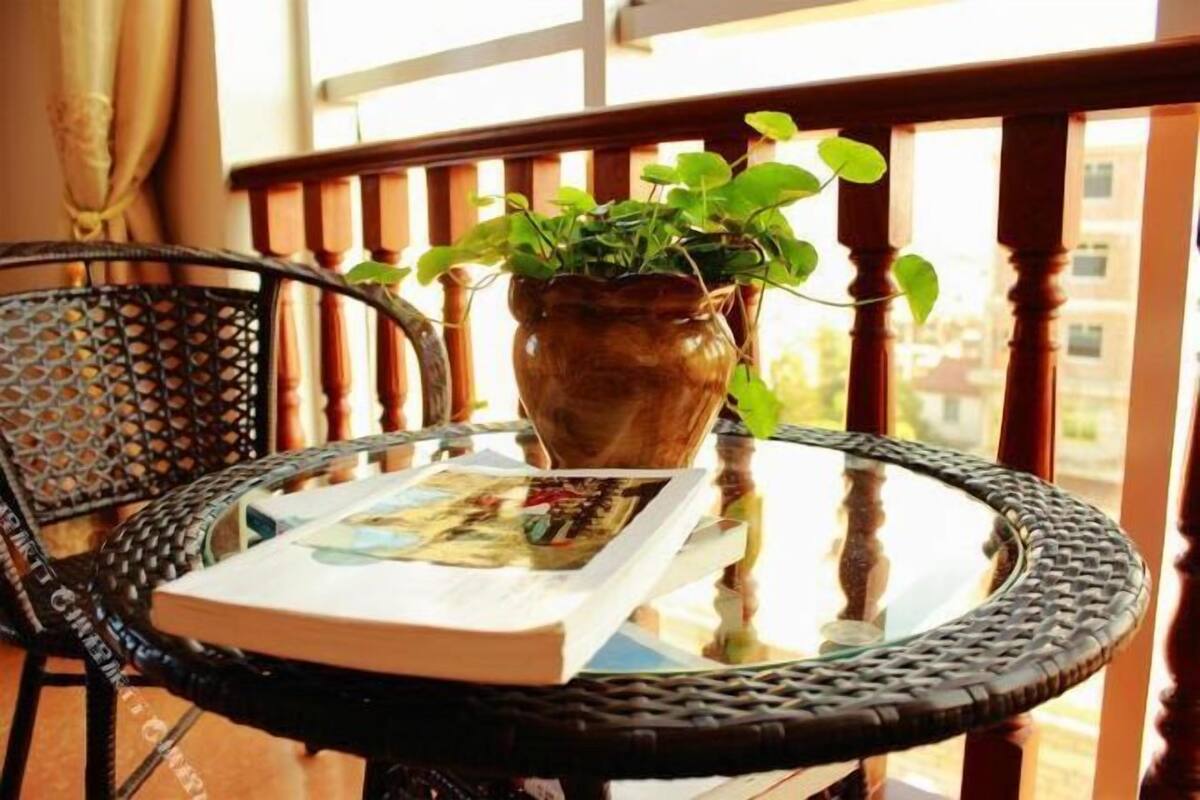 A round table with a book and a potted plant on it, set on a balcony with a wooden railing.