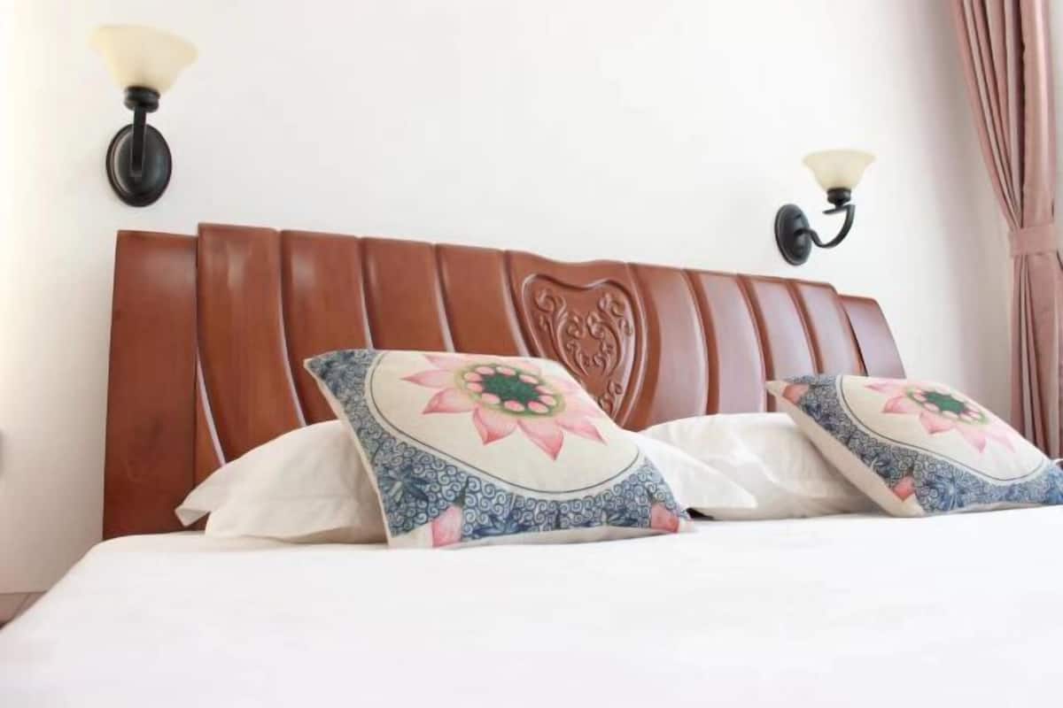 A bed with a wooden headboard, two wall-mounted lamps, and decorative pillows.