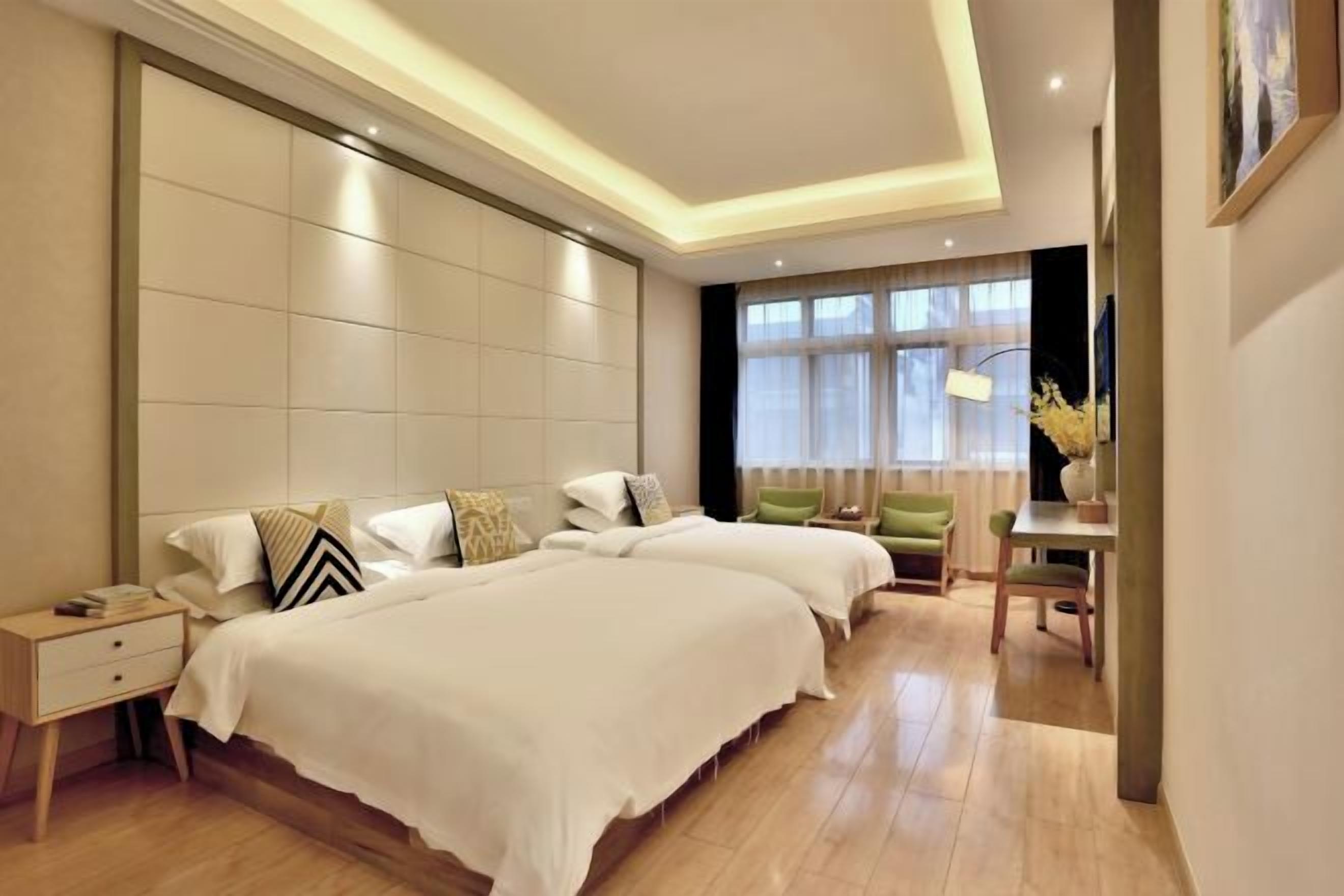 A modern hotel room with two beds, a desk, and a chair.