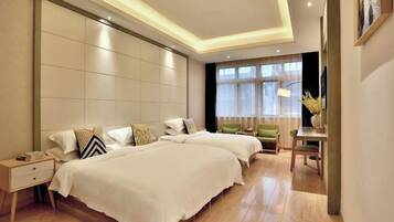 A modern hotel room with two beds, a desk, and a chair.