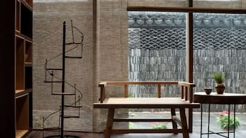 A room with a wooden bench, a floor lamp, and a view through a large window.