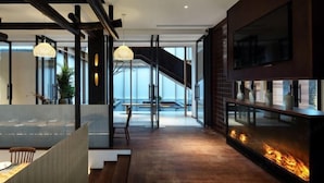 A modern interior with a fireplace, a dining area with a view, and a staircase leading to a balcony. - Shuiyunju Boutique Hotel (Tongxiang)