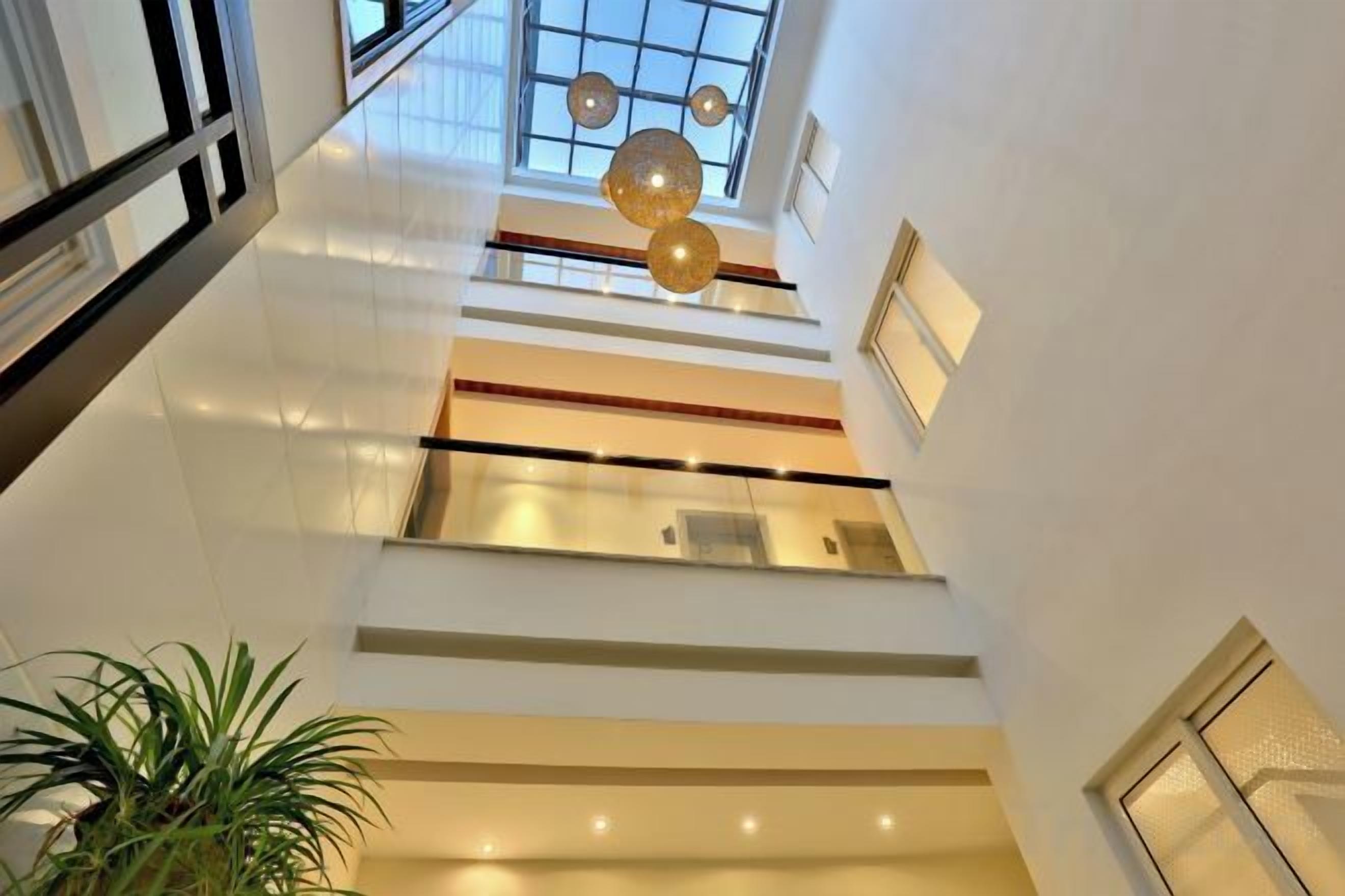 A multi-level interior with a staircase, glass railings, and pendant lighting.