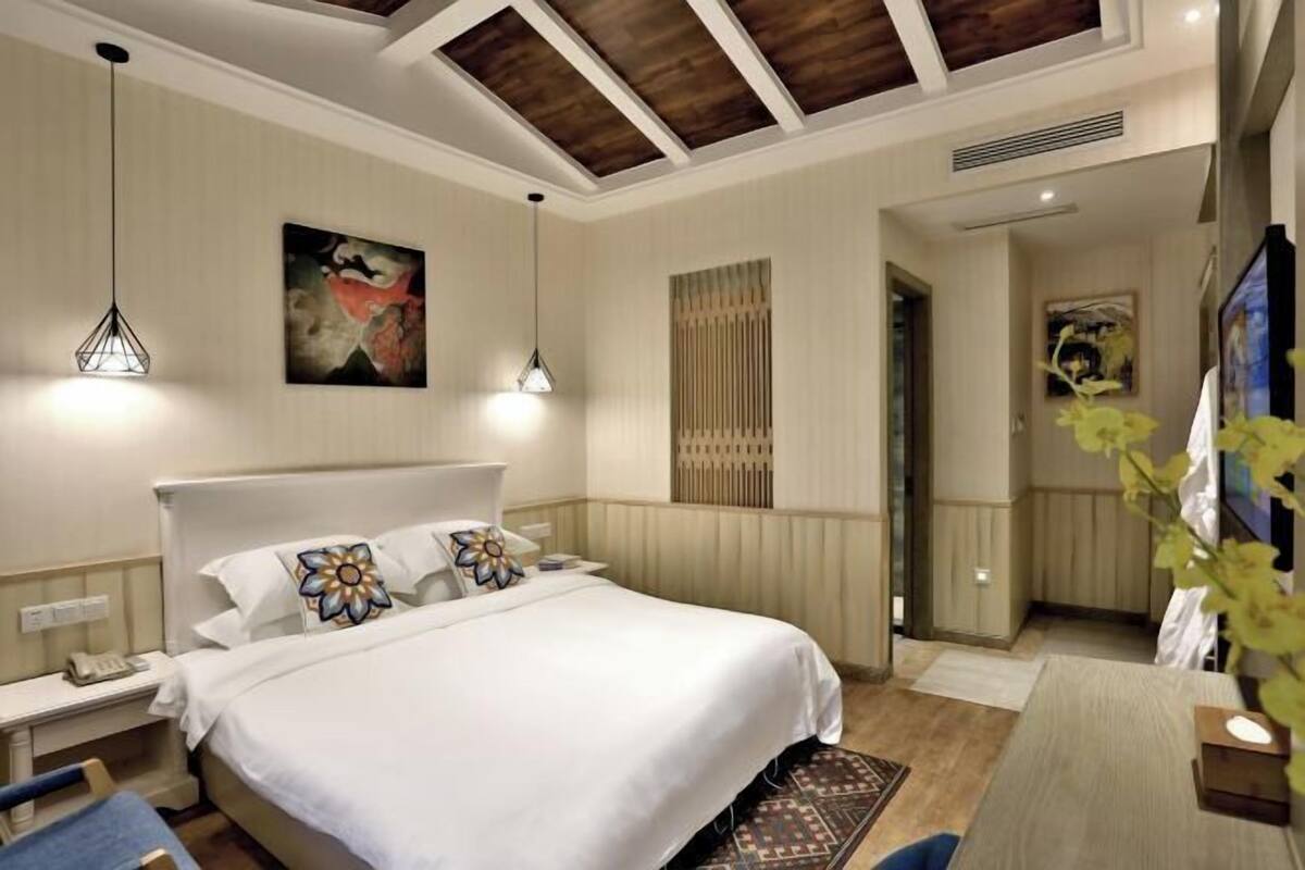 A hotel room with a bed, bedside tables, a desk, and a chair.