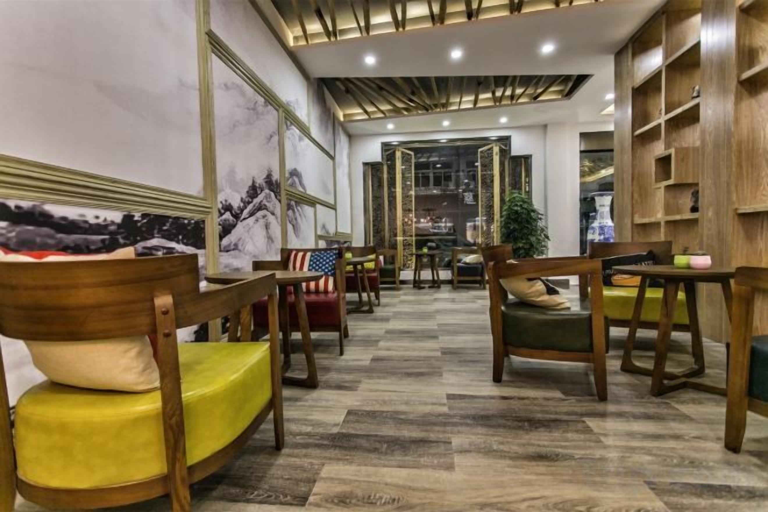 Un vestíbulo de hotel con mobiliario de madera, piso estampado y vista al área de comedor.