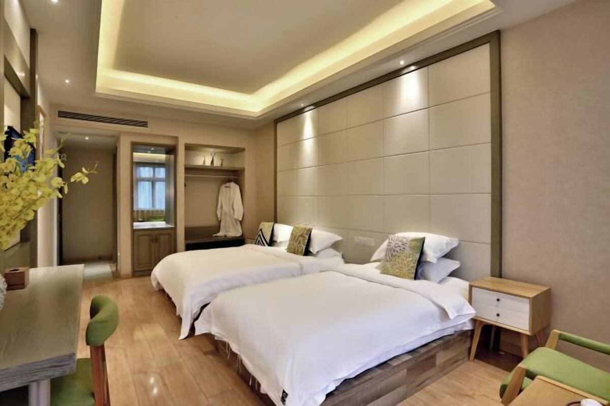 A hotel room with two beds, a desk, a chair, a nightstand, and a wardrobe.