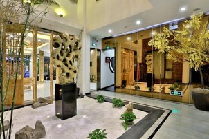 Un vestíbulo con diseño moderno, que presenta una escultura central, un escaparate de vidrio y plantas de interior.