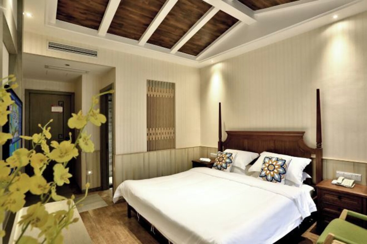 Habitación de hotel con una cama grande, un cabecero de madera, una mesita de noche y una mesilla.
