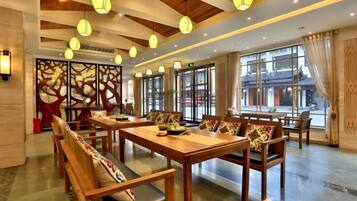A spacious dining area with wooden tables and benches, large windows, and hanging pendant lights.