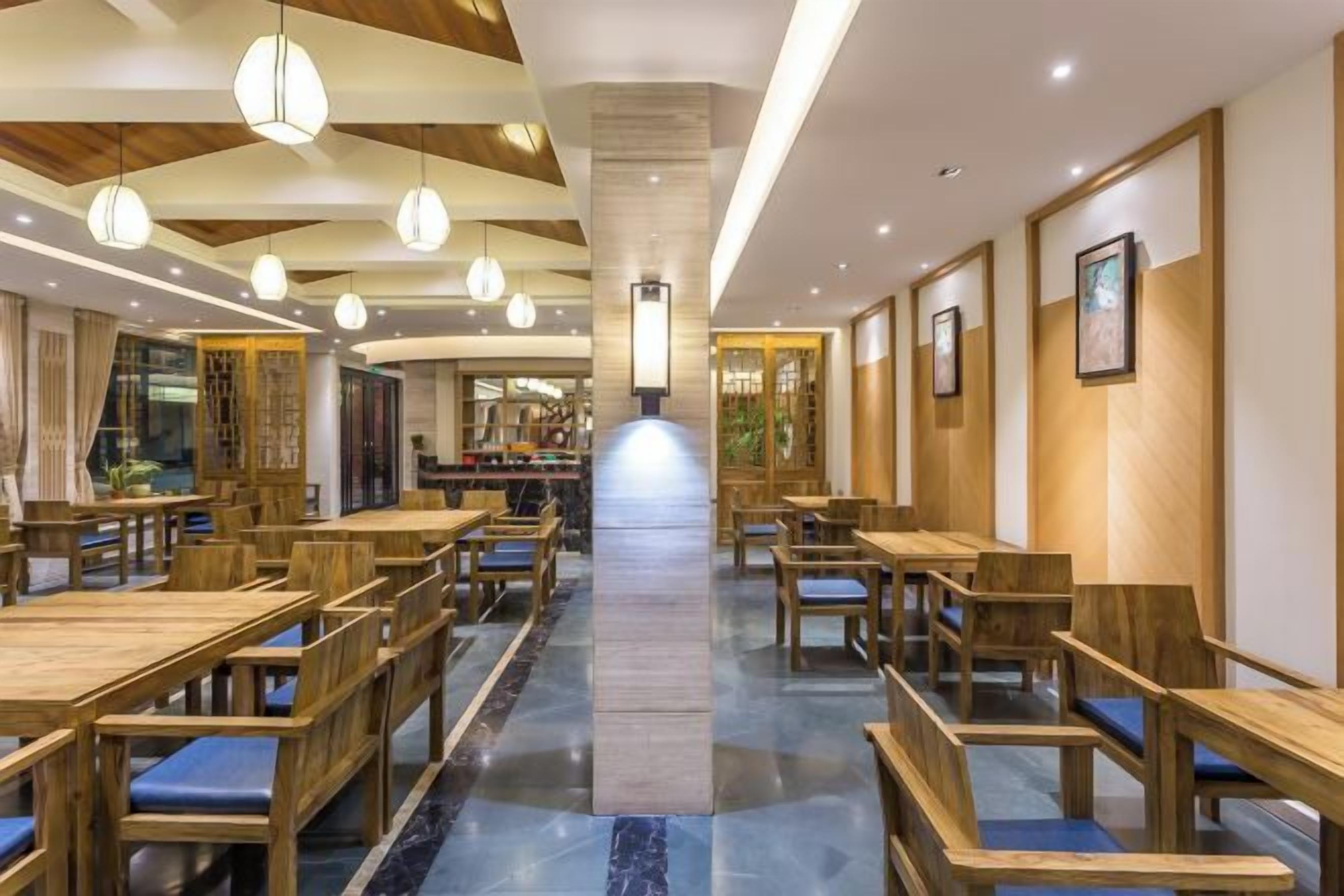 A restaurant with wooden tables and chairs, a central walkway, and pendant lighting.