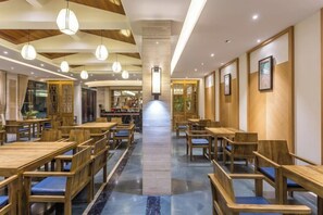 A restaurant with wooden tables and chairs, a central walkway, and pendant lighting.