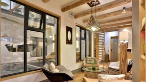 A modern interior with a wooden ceiling, large windows, and a seating area with a glass table. - Shuiyunju Boutique Hotel (Tongxiang)