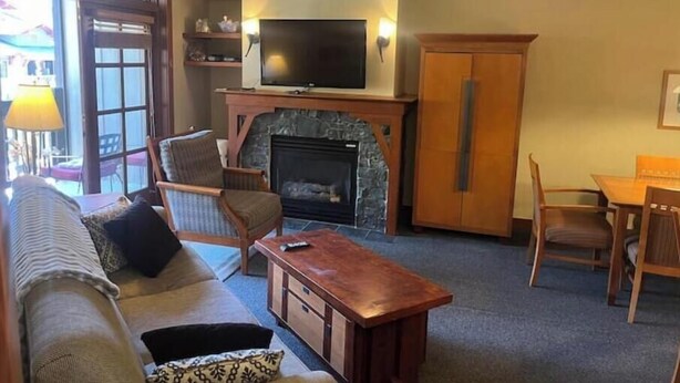 A living room with a sofa, chairs, a television, a fireplace, and a dining area.