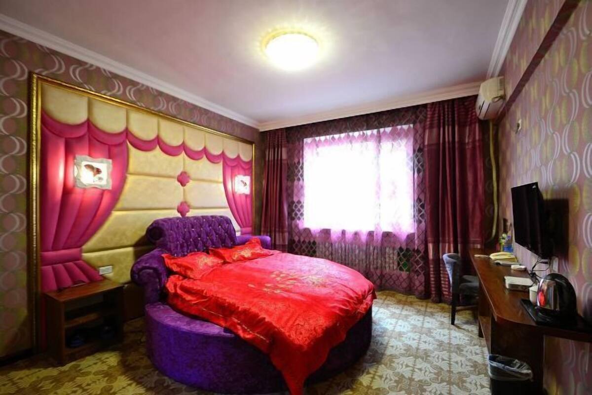 Een slaapkamer met een groot bed, een bureau en een televisie.