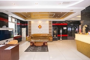 A hotel lobby with a reception desk, a sofa, a patterned rug, and a decorative wall. - Harbin Nantian Huilong Hotel (Harbin)