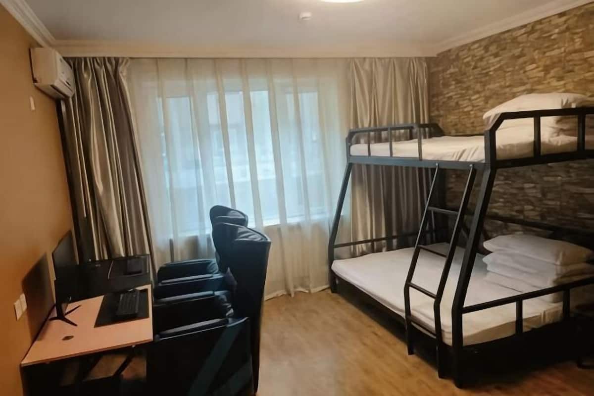 Een slaapkamer met stapelbed, bureau, stoel en computer.