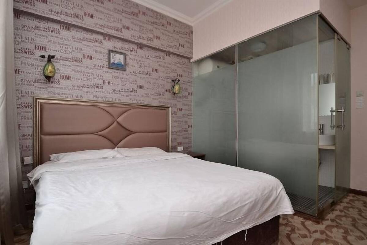 Een hotelkamer met een bed, een kledingkast en een muur met namen van steden.