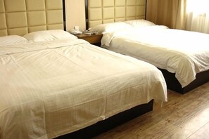 Twee bedden met hoofdborden, een nachtkastje en een houten vloer.