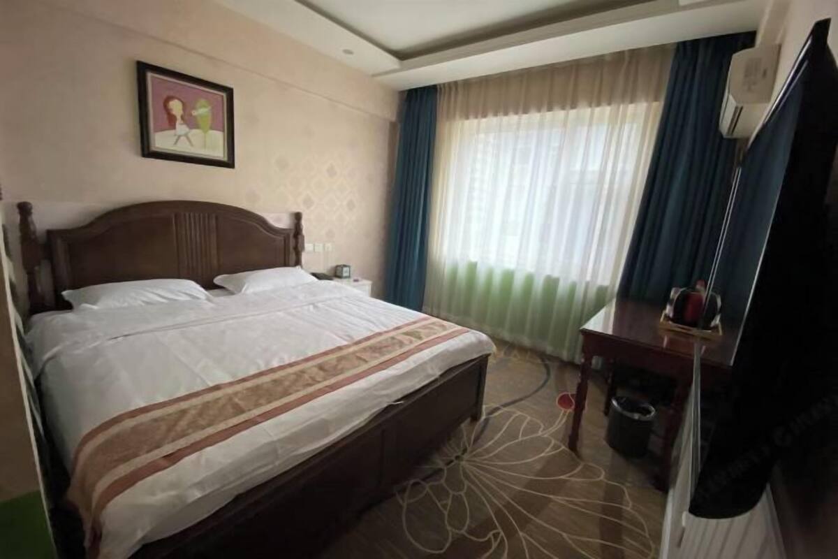 A hotel room with a bed, a desk, a chair, a television, and a picture on the wall.