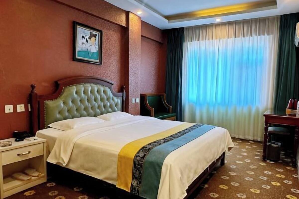 A hotel room with a large bed, a nightstand, a desk, and a chair.
