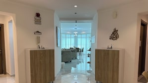 Een hotel receptie met een marmeren vloer, twee houten receptiebalies, een eetgedeelte op de achtergrond en een modern interieur.