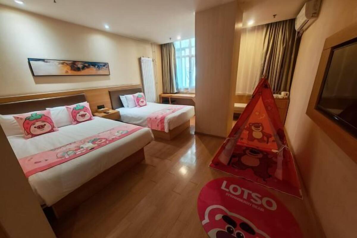 A hotel room with two beds, a desk, and a window with curtains.