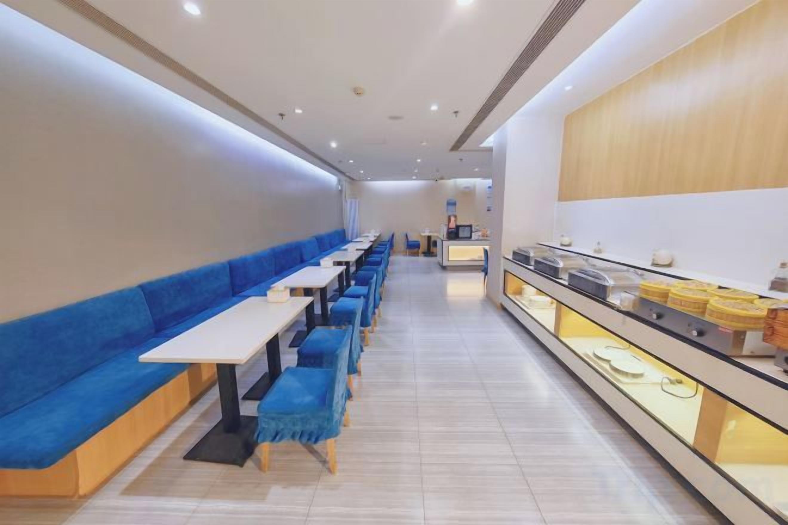 A restaurant with long tables and blue cushioned seating along the walls.